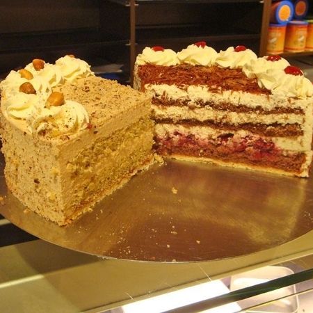Stück heller Kuchen mit lockerer Creme und Nüssen auf goldener Oberfläche