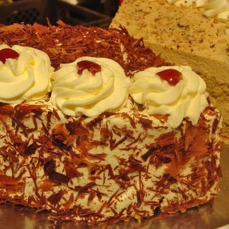 Stück Sahnekuchen mit heller Creme und Nussdekor auf goldener Oberfläche
